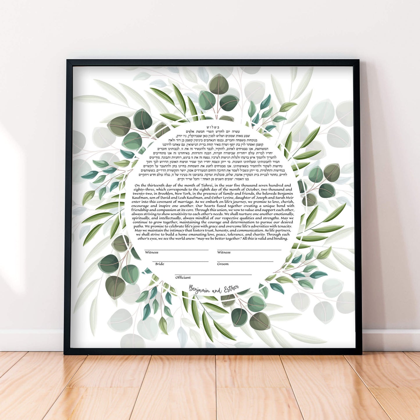 Botanical greenery wreath ketubah displayed in a black frame.
