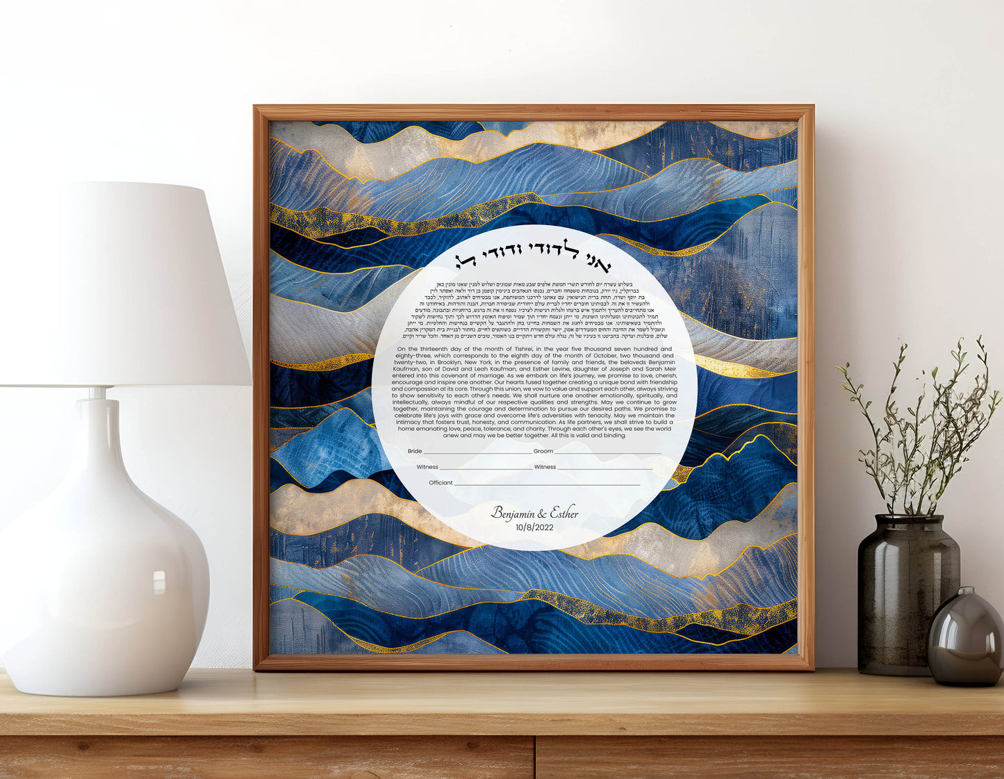 Framed ketubah with blue and gold abstract design on a wooden shelf.