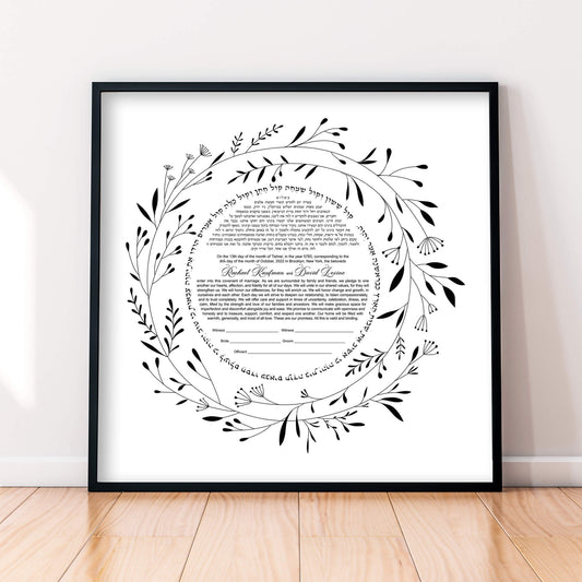 A beautiful minimalist floral hand-drawn ketubah featuring a laurel wreath displayed in a black frame.